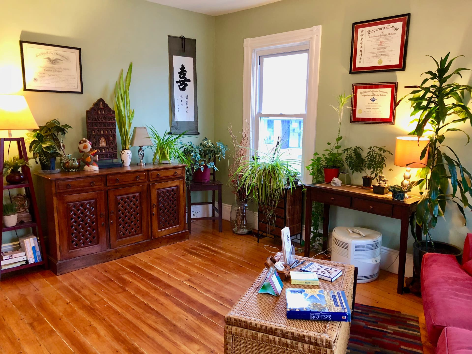 Reception nook with wooden cabinet, plants, and calligraphy scroll