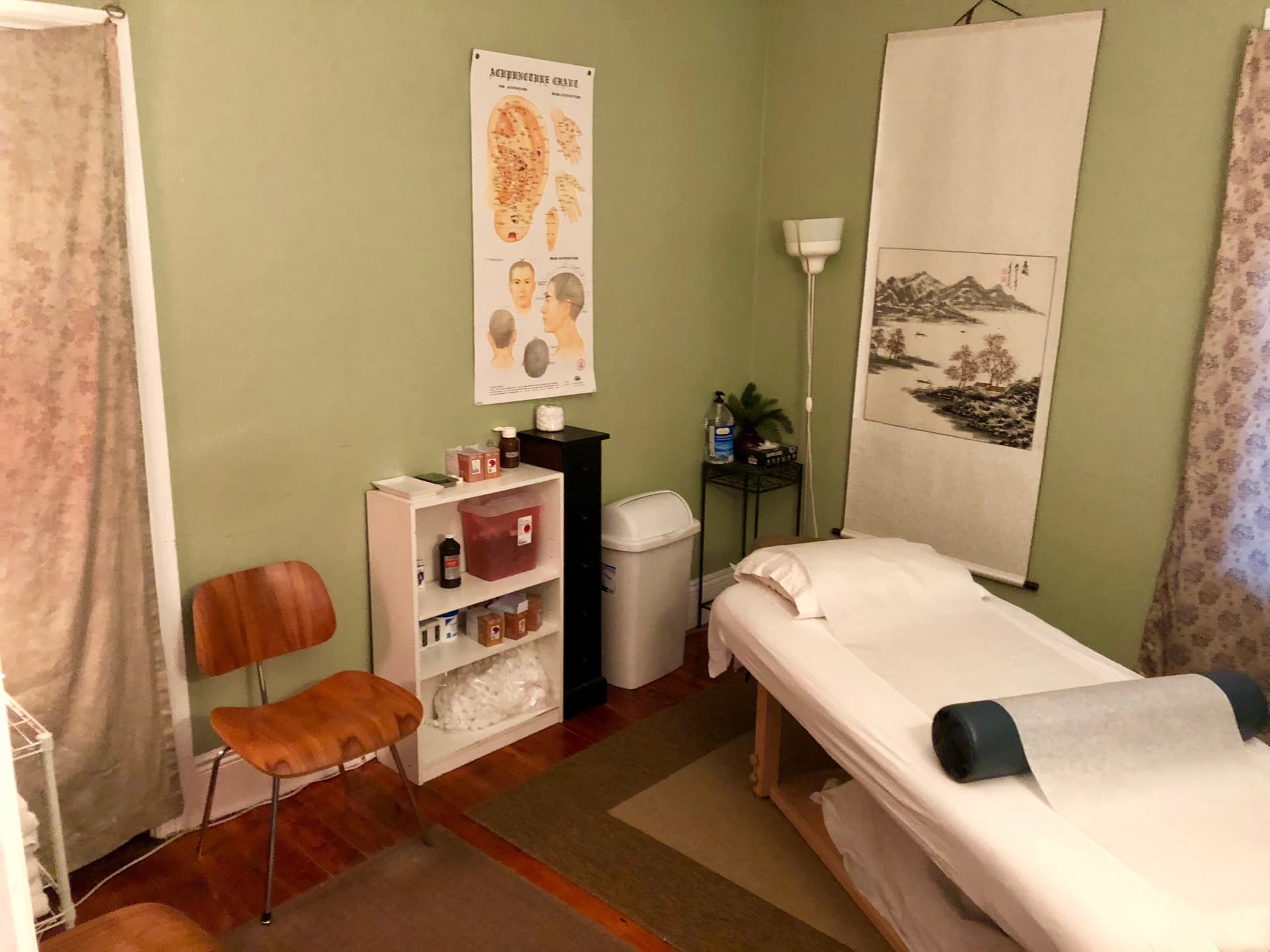 Treatment room with ear and hand acupuncture chart and a hanging scroll painting